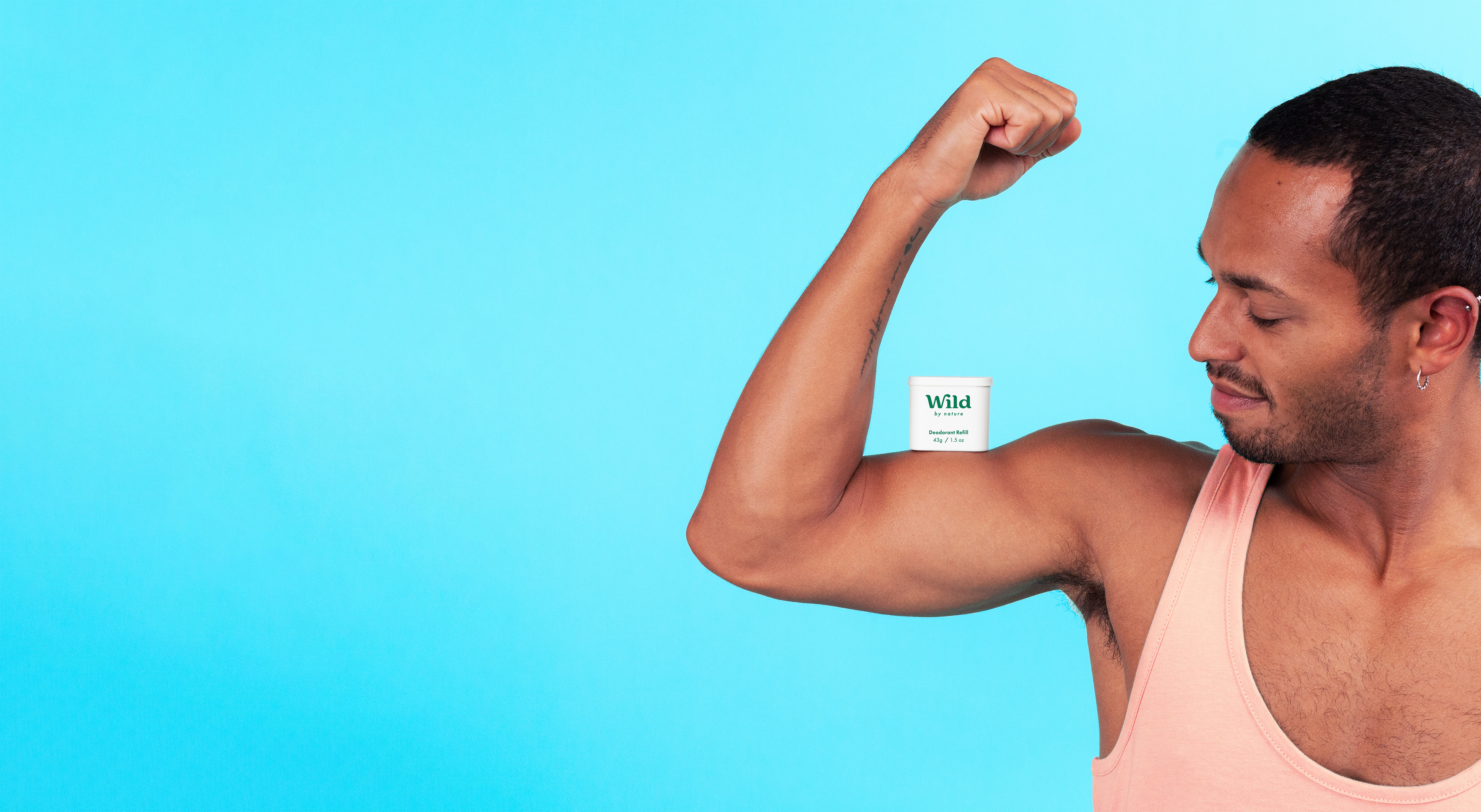 A man tensing his bicep with a Wild deodorant refill balancing on his arm muscle