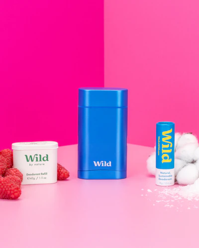 Pie de foto: frambuesas, yogur y un recipiente azul sobre una mesa rosa