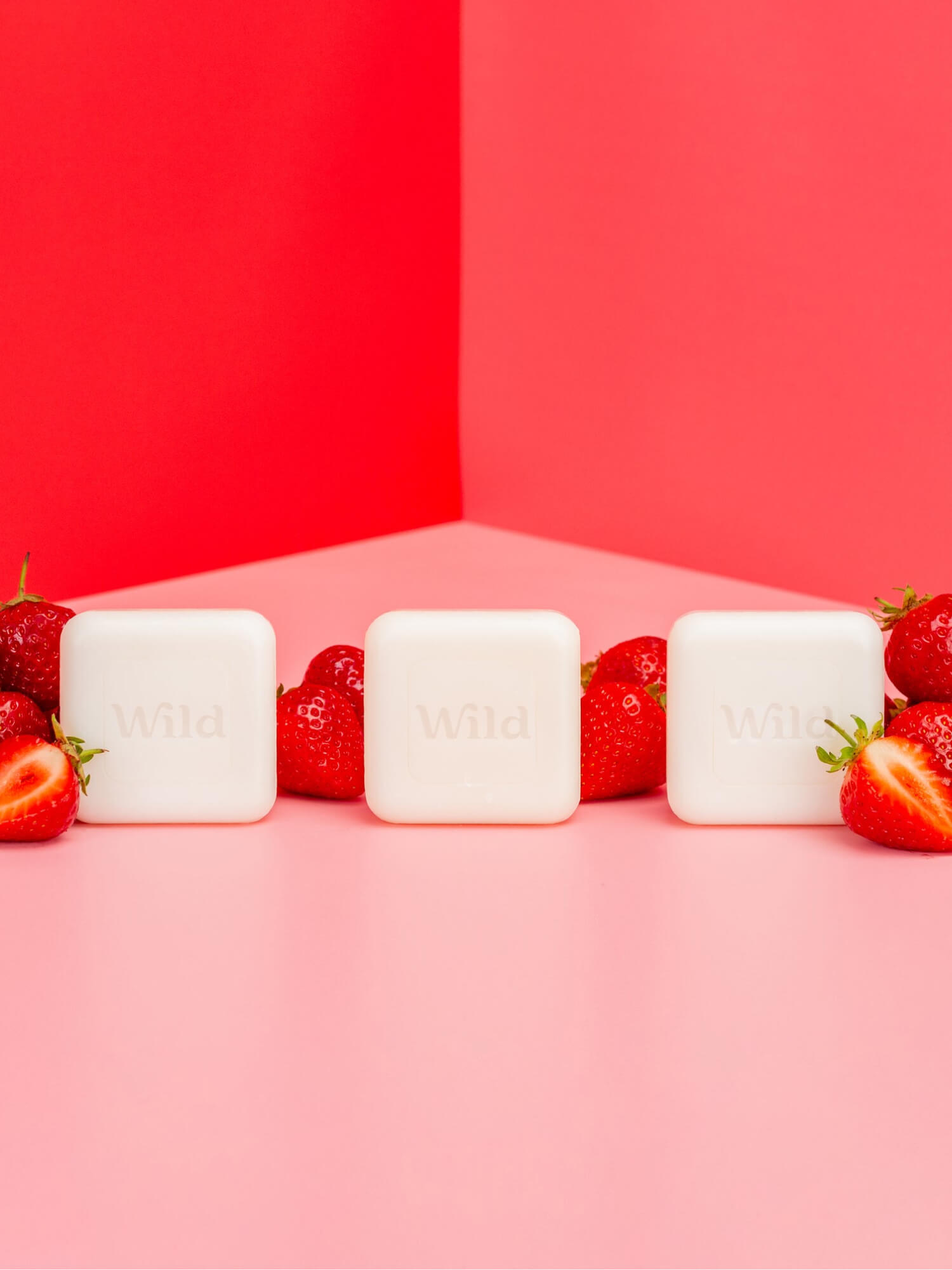 Bildunterschrift: drei Seifenstücke mit Erdbeeren auf einer rosa Oberfläche