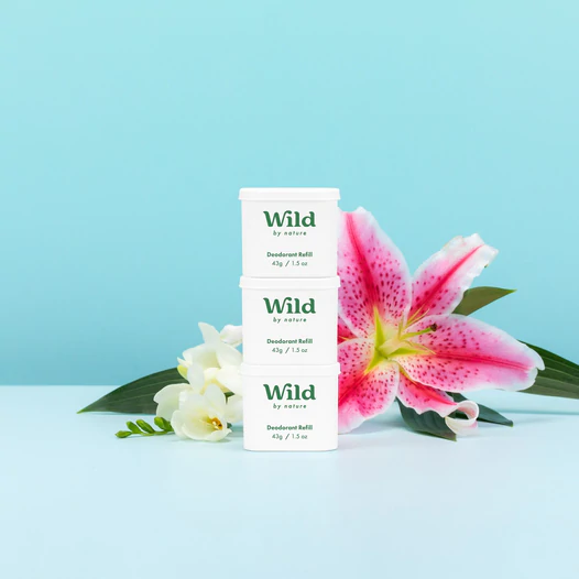 Caption: a pink flower sitting next to a pack of wild deodorant