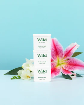 Caption: a pink flower sitting next to a pack of wild deodorant