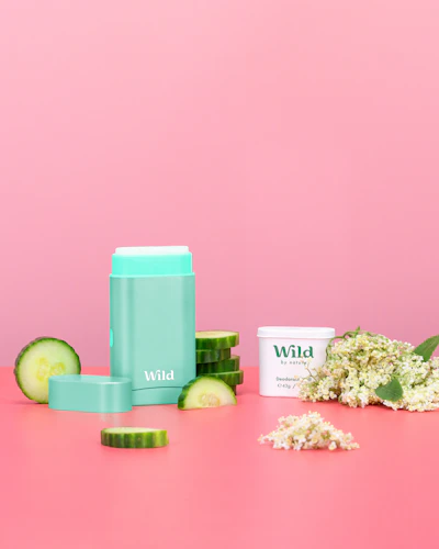 Caption: a pink table topped with a container of cream and cucumber
