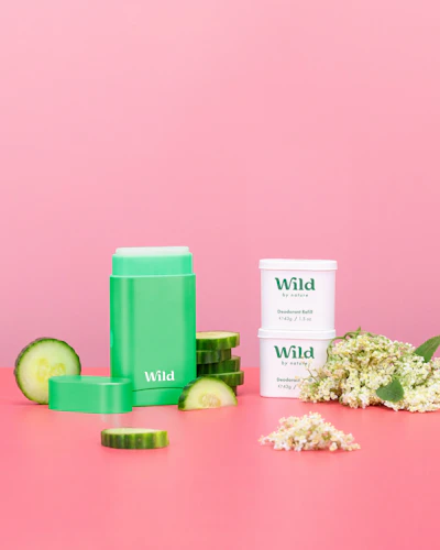 Caption: a pink table topped with green containers and a cucumber