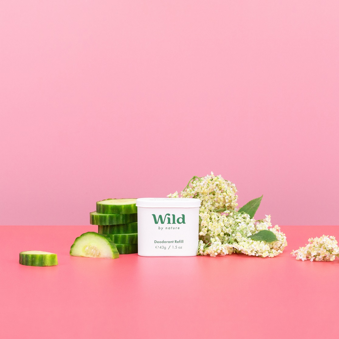 Caption: a pink table with a container of wild and a cucumber next to it