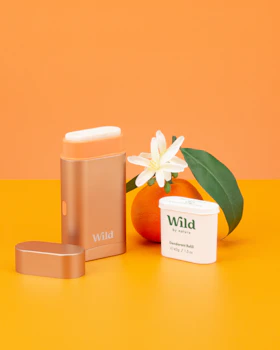 Légende : un flacon de soin pour la peau sauvage à côté d'une orange