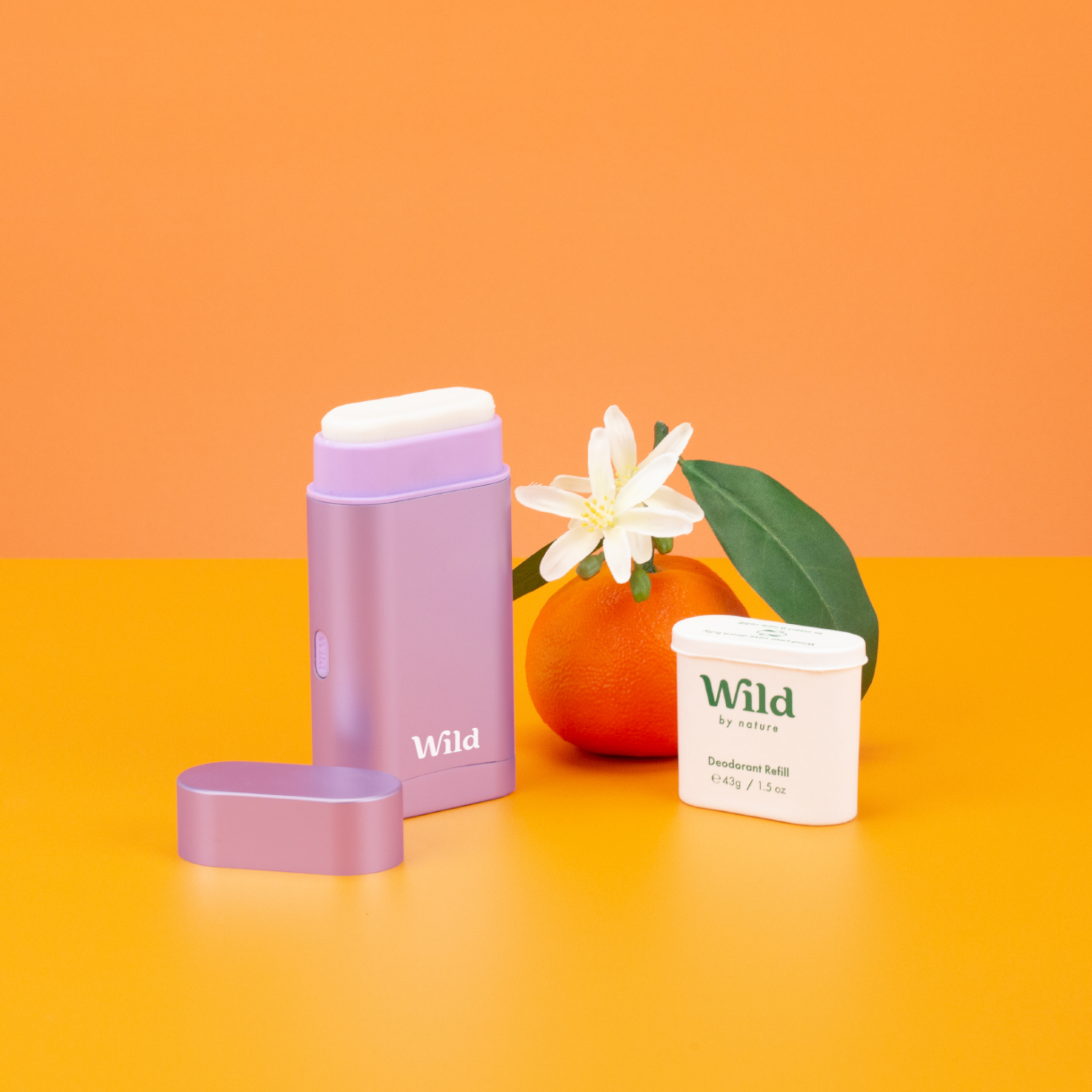 Caption: an orange, a cup, and a container sitting on a table