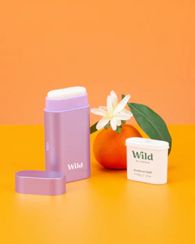 Légende : une orange, une tasse et un récipient posés sur une table