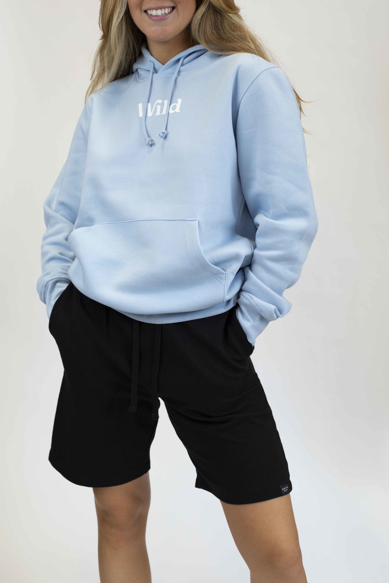 Caption: a woman wearing a light blue hoodie and black shorts