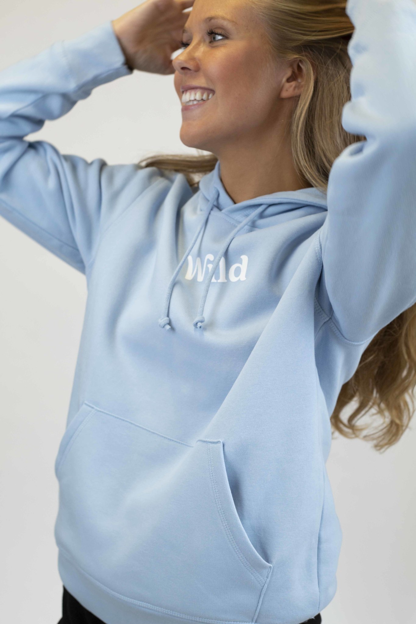 Caption: a woman wearing a light blue hoodie with the word wild printed on it