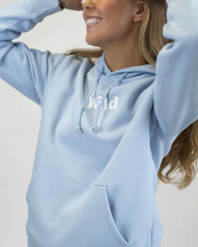 Caption: a woman wearing a light blue hoodie with the word wild printed on it