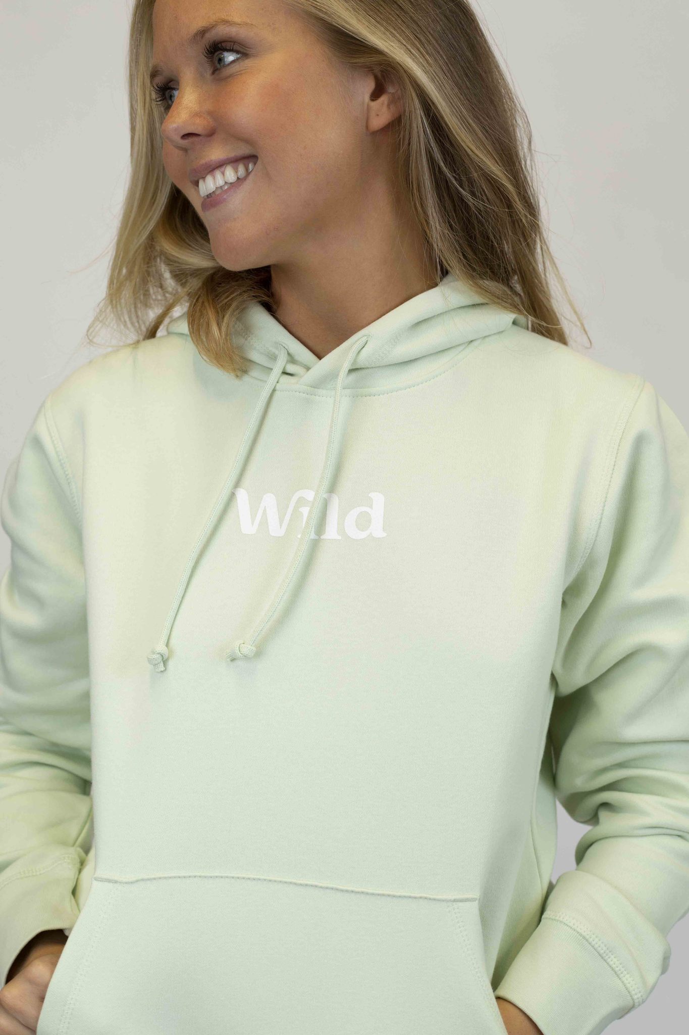 Caption: a woman wearing a light green hoodie with the word wild printed on it