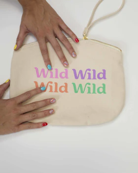 Caption: a woman's hands holding a white pouch with the words wild wild on it