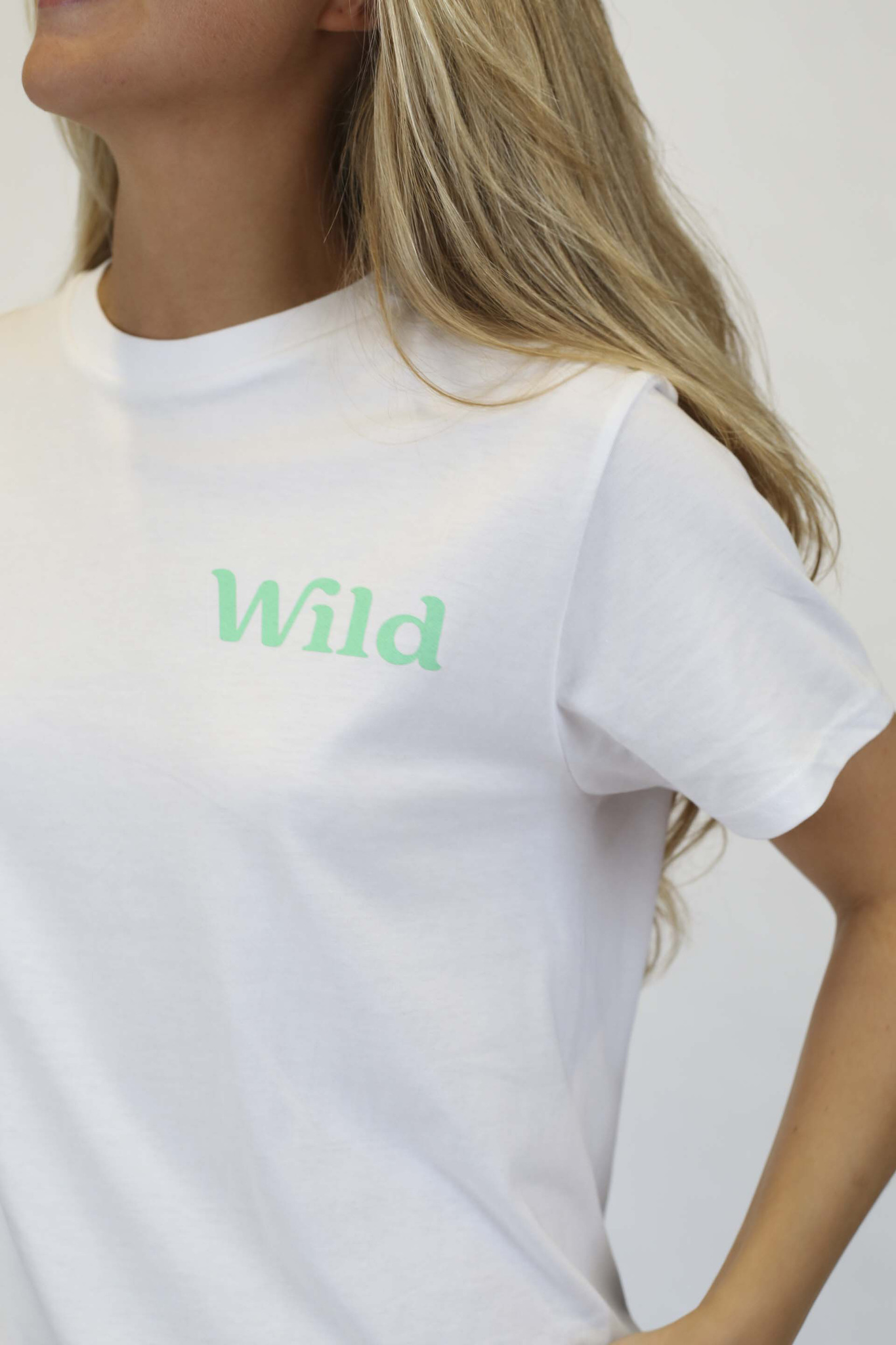 Caption: a woman wearing a white t - shirt with the word wild printed on it
