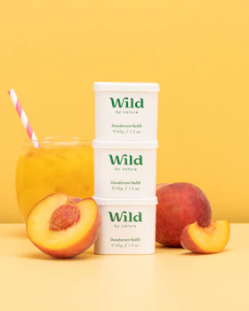 Bildunterschrift: drei Behälter mit Wildpfirsich-Tee neben Pfirsichen