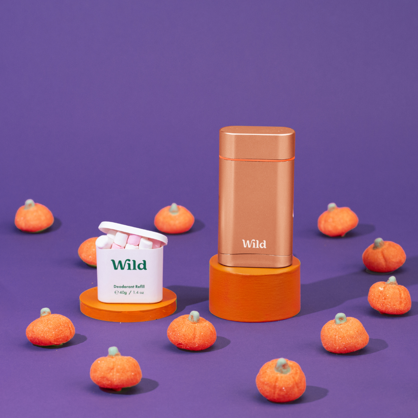 Bijschrift: een paarse achtergrond met oranje pompoenen en een container met wild