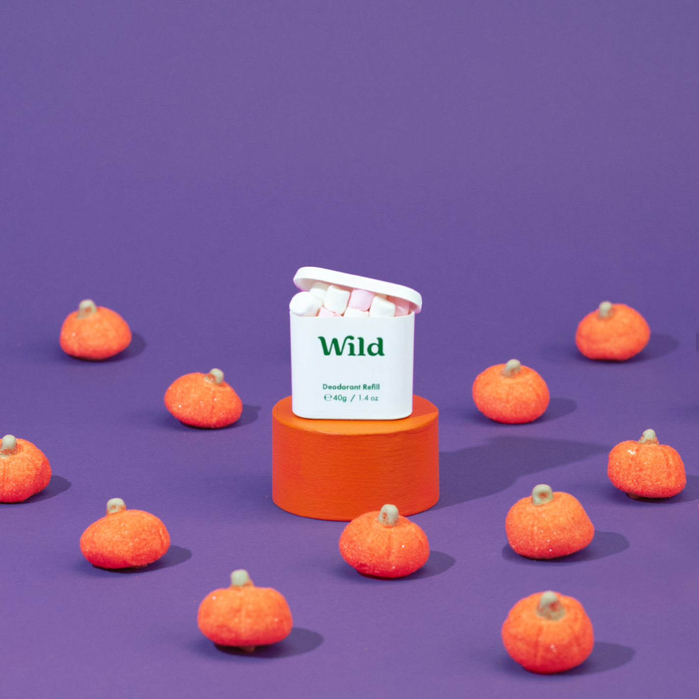 Bijschrift: een groep oranje pompoenen bovenop een paars vlak