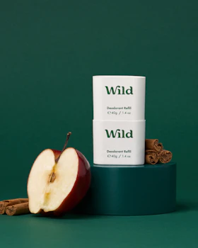 Caption: a tube of wild deodorant next to an apple