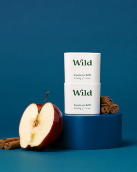 Caption: an apple and cinnamon stick next to a tube of wild