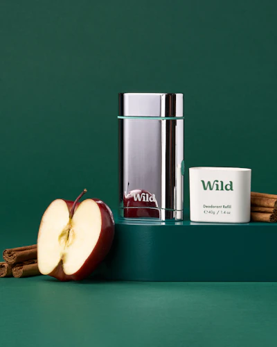 Caption: an apple, cinnamon sticks, and a glass of water on a green surface