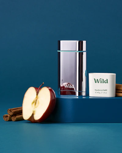 Caption: an apple, cinnamon sticks, and a glass of water on a blue surface