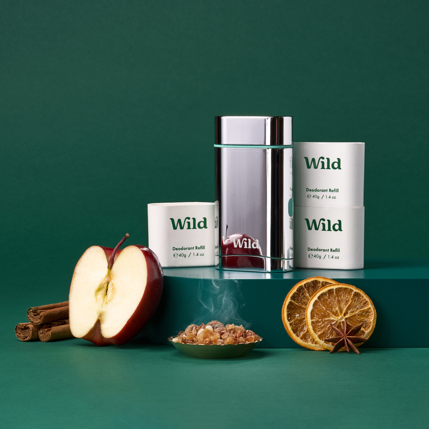 Pie de foto: una manzana, canela, naranja y canela en rama sobre una superficie verde