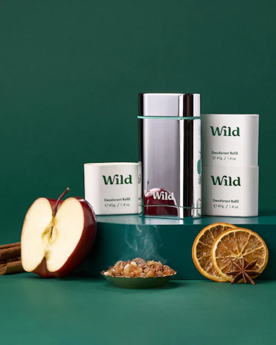 Caption: an apple, cinnamon, orange, and cinnamon stick on a green surface