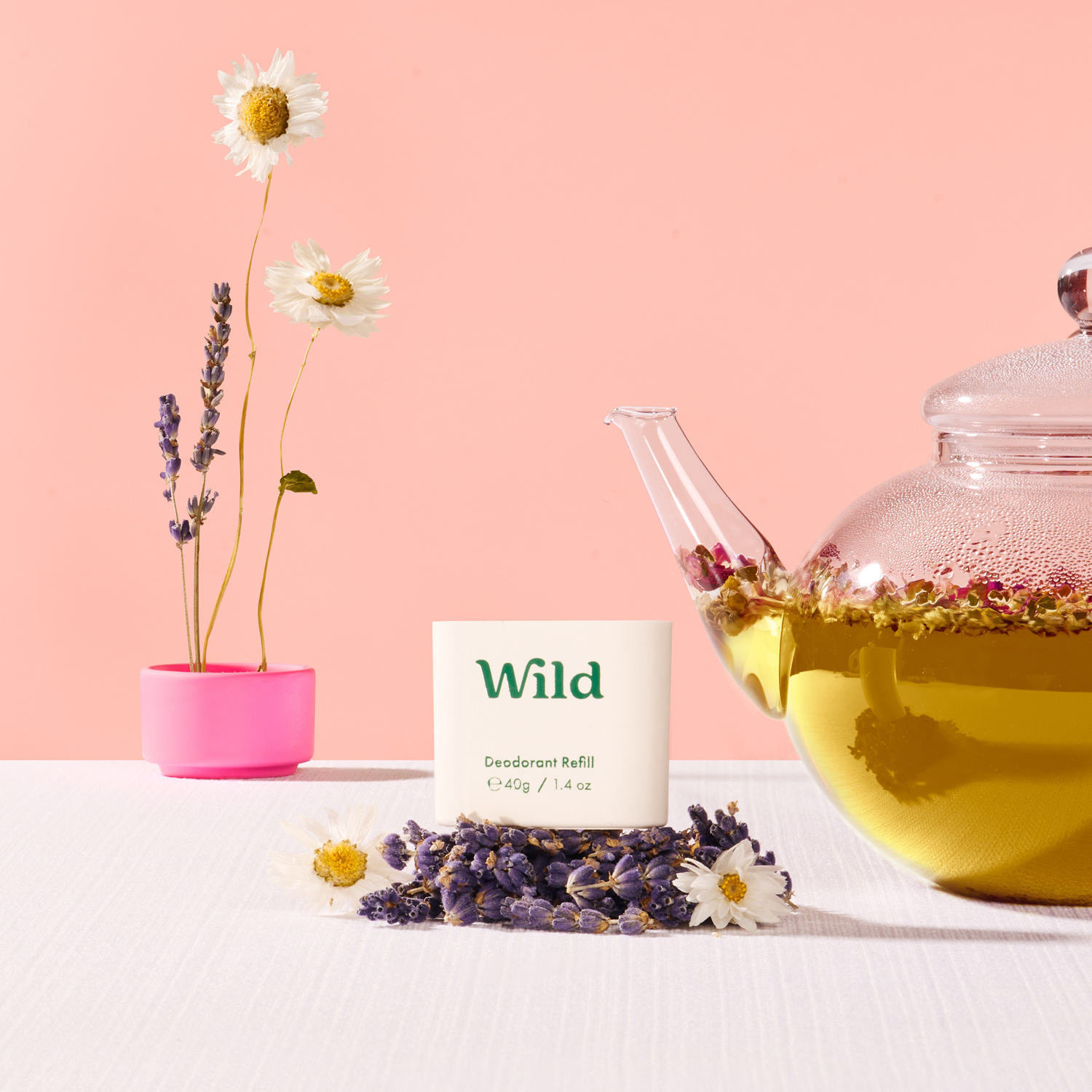 Bildunterschrift: eine mit Wildblumen gefüllte Teekanne neben einem Teebeutel