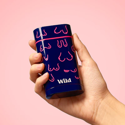 A hand holds a dark blue deodorant case with pink boobs and the word "Wild" in white lettering.