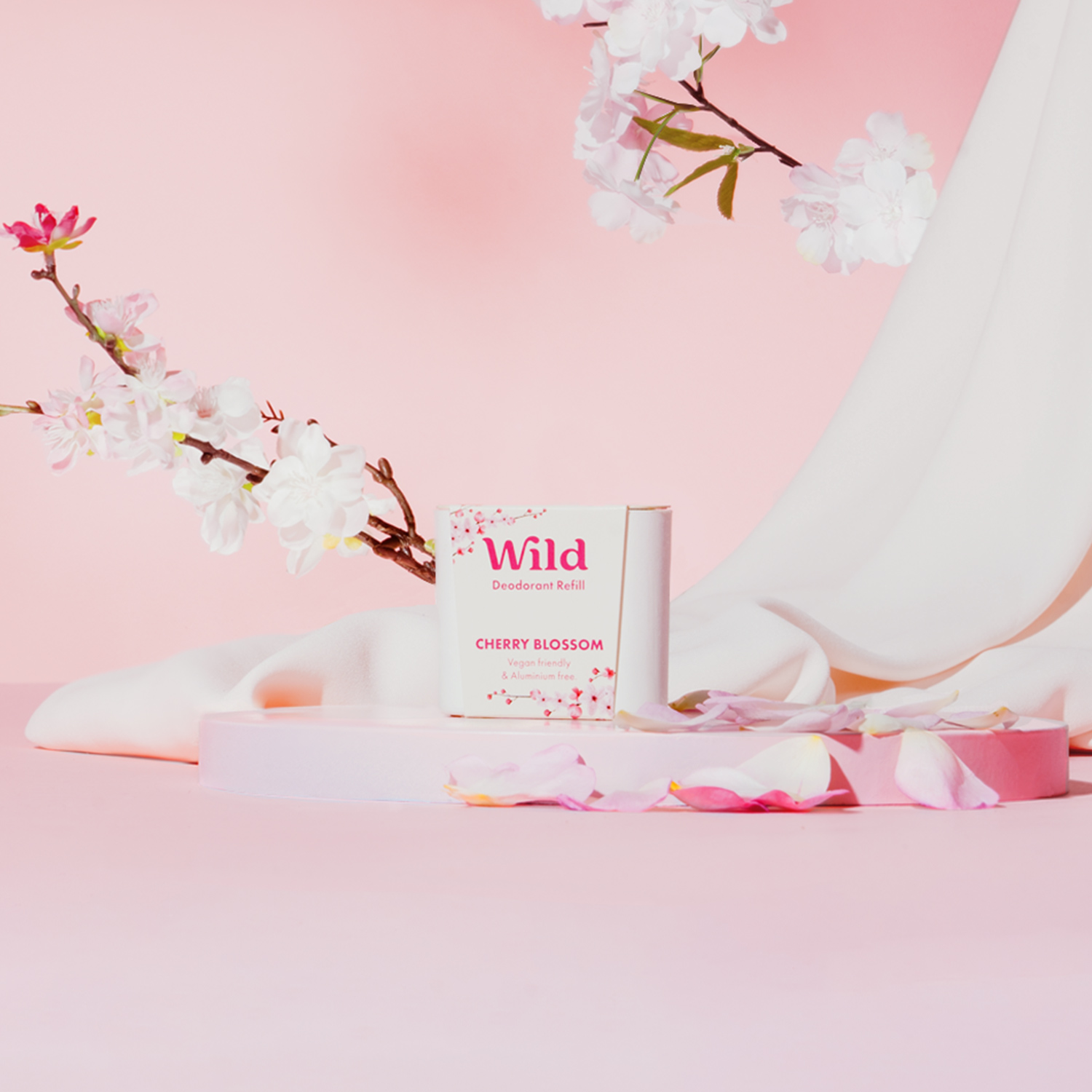 Caption: a pink background with white flowers and a white tube of cream