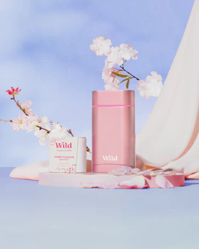 Caption: a pink vase with flowers and a pink tube next to it