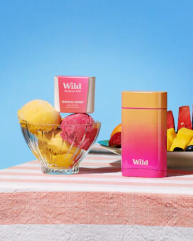Caption: a table topped with a bowl of fruit next to a container of ice cream
