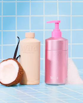 Caption: a bottle of lotion and a coconut on a blue tiled surface