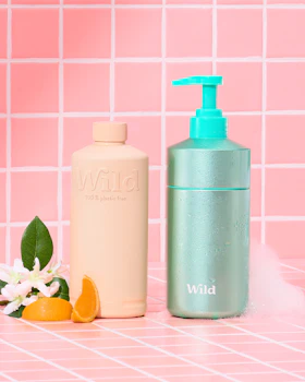 Caption: a bottle of lotion next to an orange and a soap dispenser