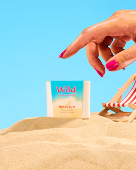Caption: a woman's hand reaching for a book on the beach