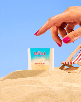 Caption: a woman's hand reaching for a book on the beach