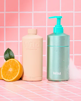 Caption: a bottle of soap next to an orange and a tube of lotion