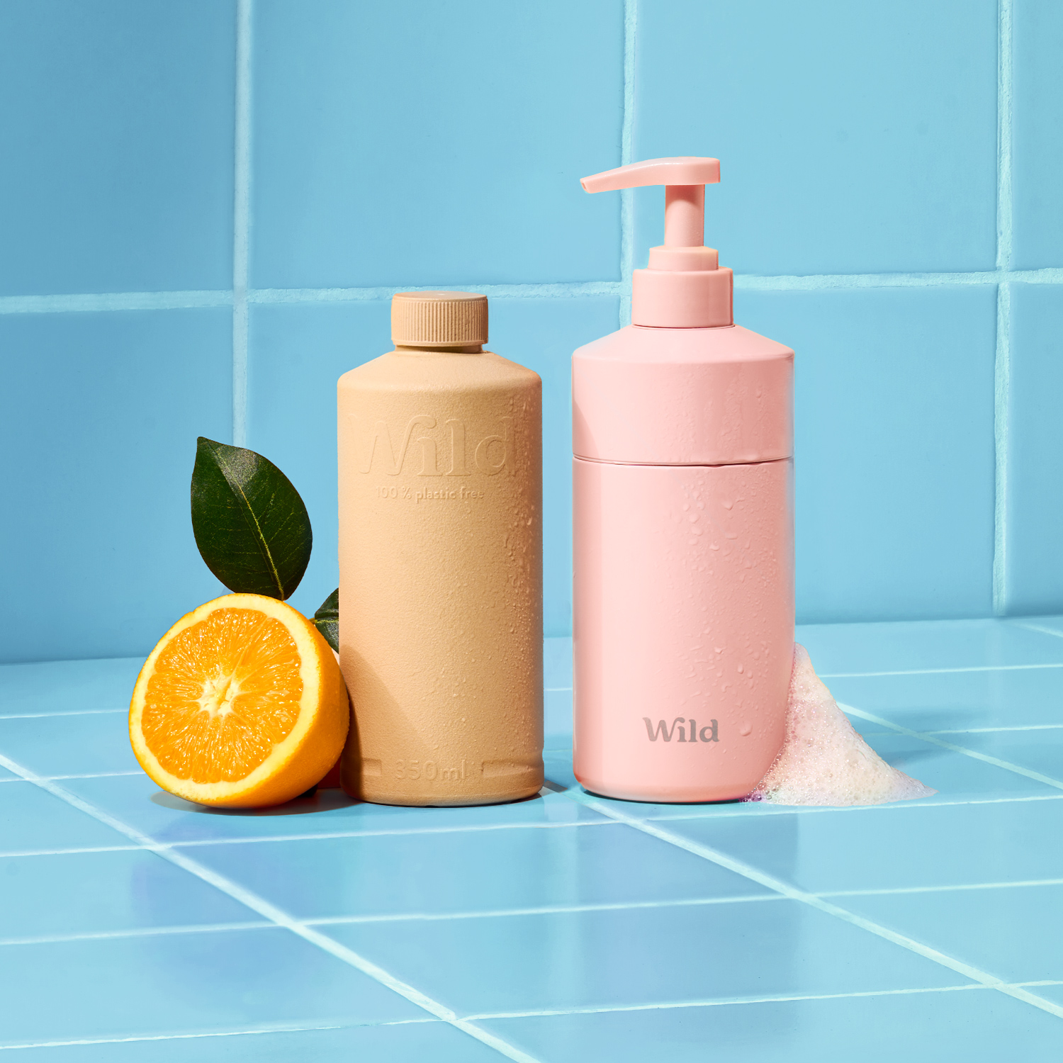 Caption: a bottle of lotion next to an orange on a blue tiled counter
