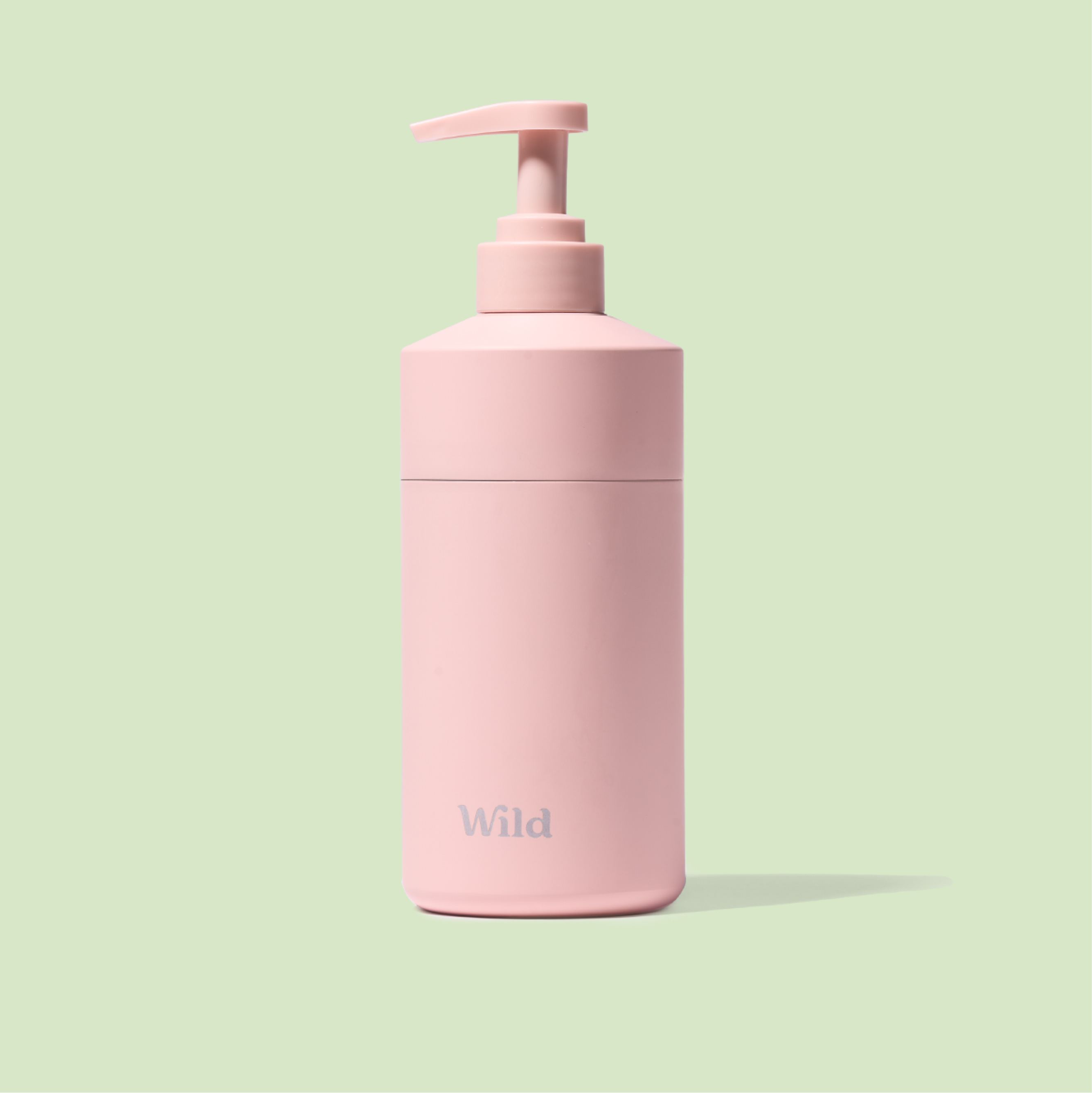 Caption: a pink hand soap dispenser on a green background