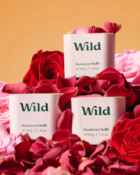 Caption: three packages of wild deodorant next to pink roses