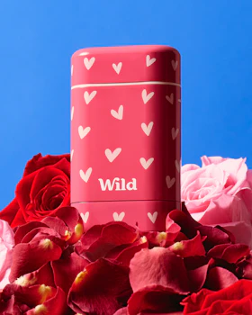 Caption: a close up of a can of wild cosmetics surrounded by flowers