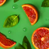 Caption: a group of sliced grapefruits with leaves on a green surface