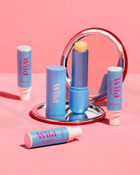 Didascalia: uno sfondo rosa con uno specchio e tre balle di labbra