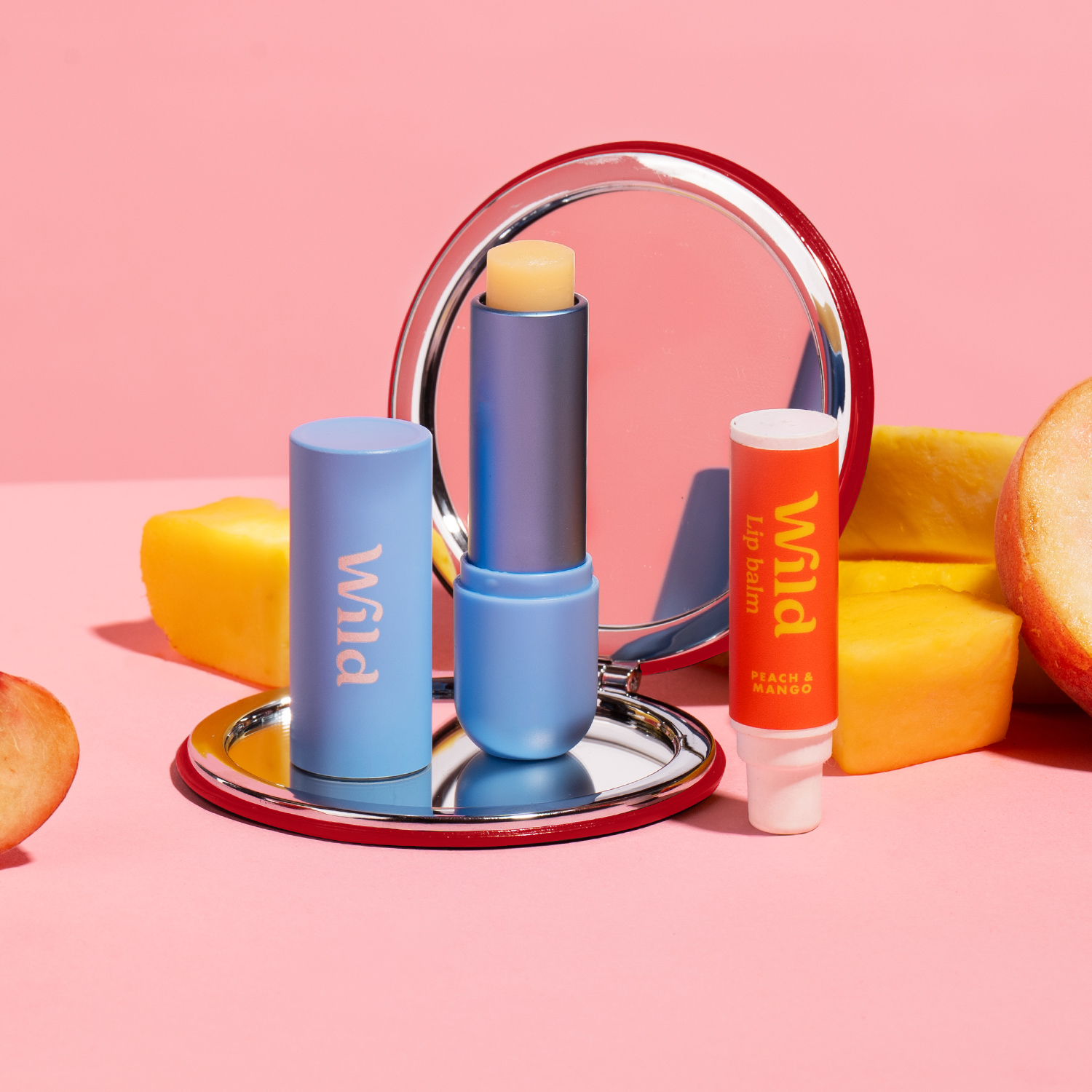 Caption: a pink background with a mirror, lipstick, and fruit