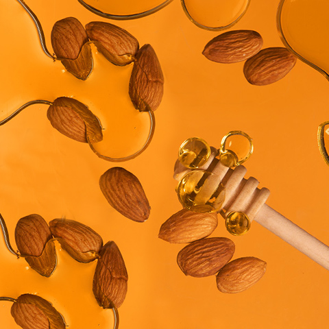 Bijschrift: amandelen en honing op een gele achtergrond