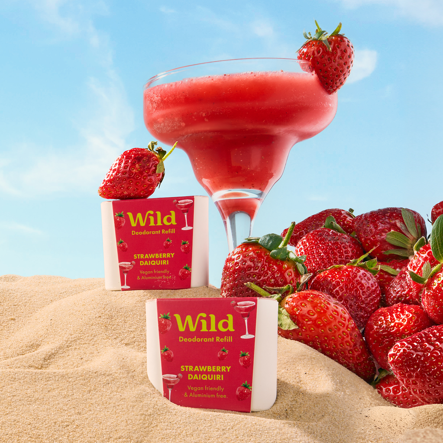 Caption: a drink and some strawberries in the sand