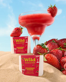 Caption: a drink and some strawberries in the sand
