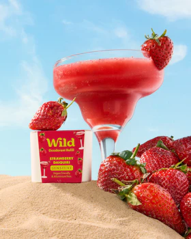 Caption: a drink and strawberries on a sandy beach