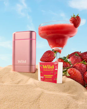 Caption: a pink mp3 player sitting on top of a pile of sand next to a drink