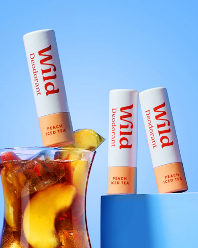 Caption: a glass filled with ice and fruit next to a tube of lip balm