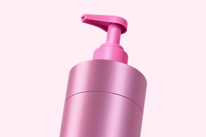 Bildunterschrift: eine rosa Flasche Lotion auf weißem Hintergrund